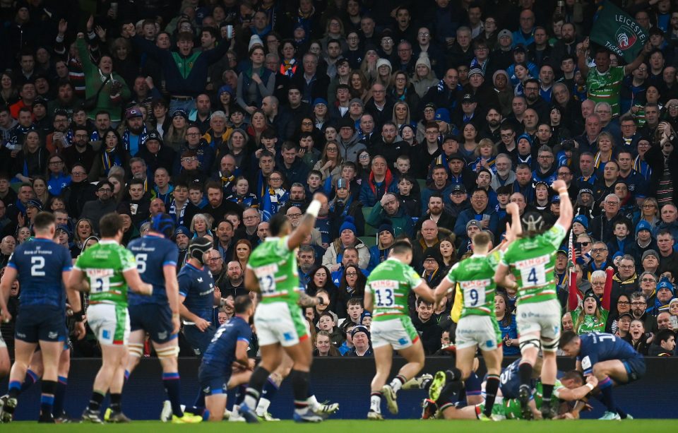 fans watch as players sprint across a rugby field